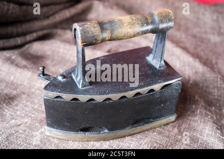 old coal iron. Ancient metal iron on brown canvas Stock Photo