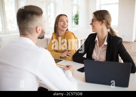 Two joyful business women happily looking at each other while spending job interview in modern office Stock Photo