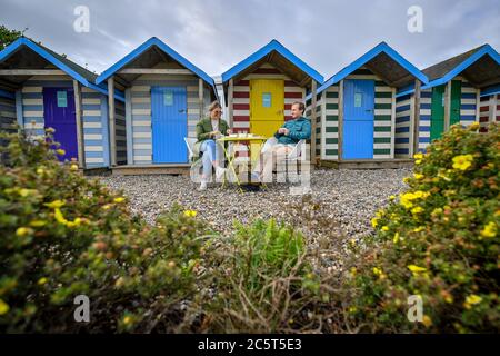 Claire Gallimore and Ben Attenborough eat their socially distanced breakfast from beach huts after staying overnight in accommodation for the first time since lockdown at St Moritz hotel, Cornwall, as the lifting of further lockdown restrictions in England comes into effect. Stock Photo