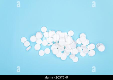 White pills on blue background.Background of large white tablets on blue paper. Pile of pills. Stock Photo