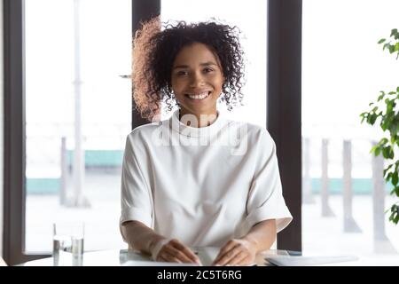 Portrait of smiling biracial female employee talk on webcam Stock Photo
