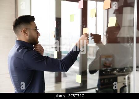 Pensive Arabic businessman develop business plan on wall Stock Photo