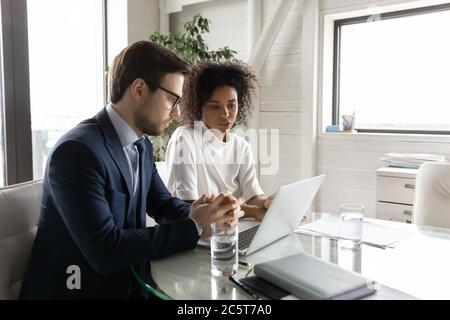 Multiethnic diverse colleagues brainstorm using laptop at briefing Stock Photo