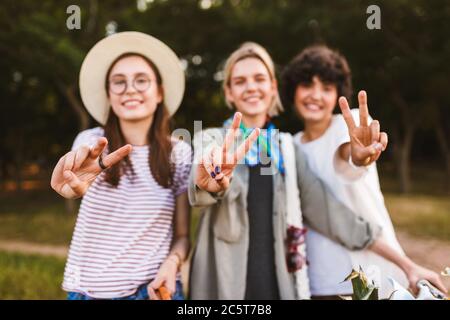 Close up smiling girls happily showing victory gestures and look Stock Photo