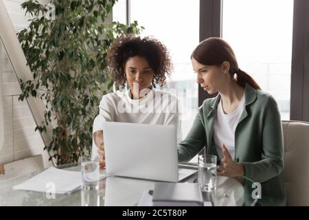 Multiracial female employees cooperate using computer in office Stock Photo