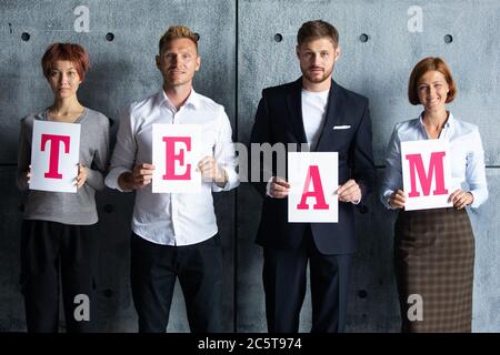Business people holding TEAM letters printed on paper Stock Photo