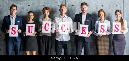Business people holding SUCCESS letters printed on paper Stock Photo