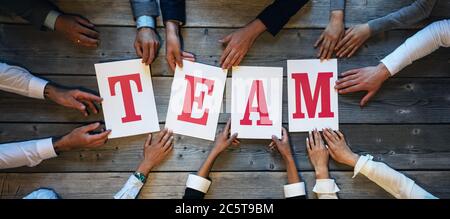 Business people holding TEAM letters printed on paper Stock Photo