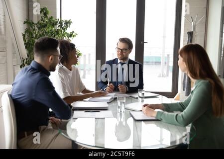 Multiethnic colleagues talk discuss business ideas at team office meeting Stock Photo