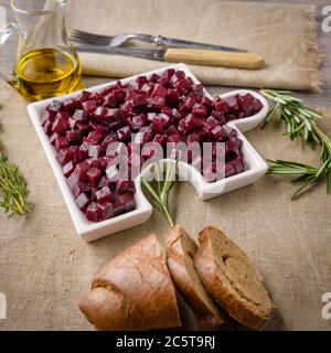 Delicious Fresh pieces of beet cube close-up with fresh onion and olive oil on a bag cloth on a rustic gray table. Beets are the root part of a beet p Stock Photo