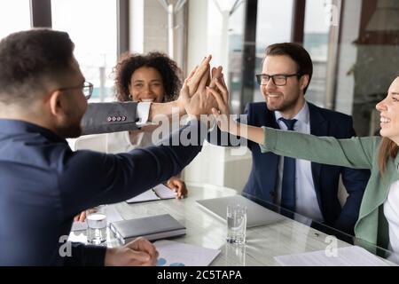 Excited multiethnic employees give high five at meeting Stock Photo