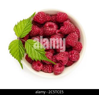 Whole ripe sweet raspberries and green leaf in a beige ceramic bowl isolated on white background. Vegetarian and healthy eating. Raw food diet. Stock Photo