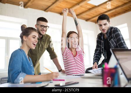 Group of cheerful business men and women happily working together in office. Young emotional people joyfully spending time at work Stock Photo