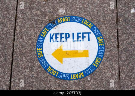 Floor sticker sign asking pedestrians to keep left as part of a one way pavement system in Southend on Sea, Essex, UK, during COVID-19 Coronavirus Stock Photo