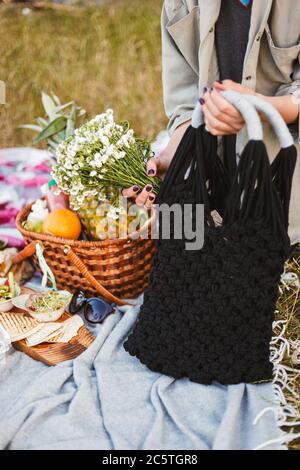 Close up photo of woman hands holding black bag and wildflowers Stock Photo