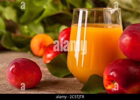 A glass of nectarine juice with fresh nectarines on rustic background Stock Photo