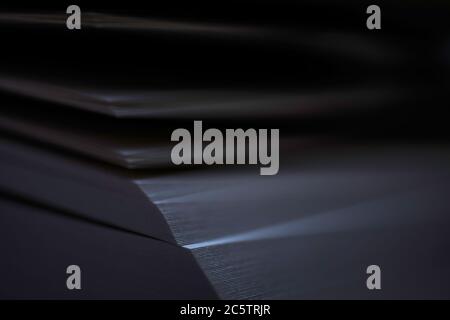 Open book in the dark with narrow depth of field. Some sheets light up. Focus on right side of papers. Stock Photo