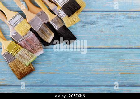 Paint various brush decorating supplies painting house renovation on old blue wooden planks top view Stock Photo
