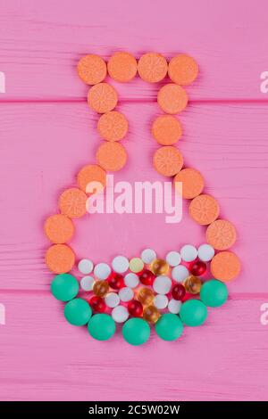 Colored round pills in a shape of a jar on pink wood. Stock Photo