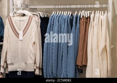 Stylish fashionable clothes on hangers in a store. Stock Photo