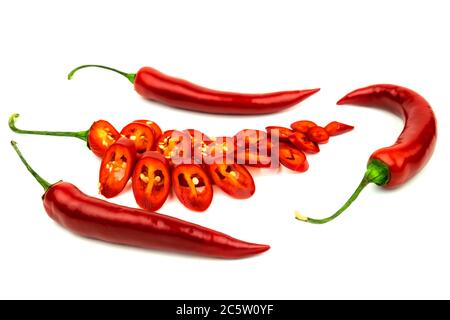 A few red hot peppers with one cut into pieces on a white background Stock Photo