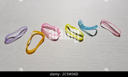 Set of small multi-colored elastic bands for hair on a white table. Stock Photo