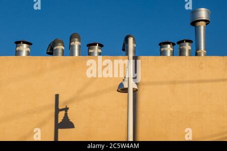 Pipes on a roof and shadows on a wall Stock Photo