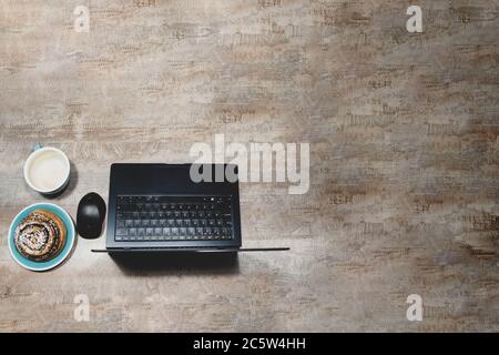 Flat layout of table with laptop, computer mouse, Cup of coffee and poppy seed bun on wooden surface, Stock Photo