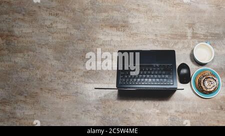 Flat layout of table with laptop, computer mouse, Cup of coffee and poppy seed bun on wooden surface, Stock Photo