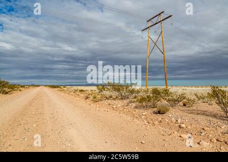 A dusty road and electricity pylons in rural New Mexico Stock Photo