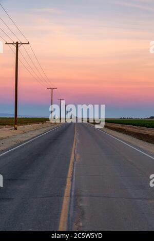 Looking down a long, straight road at sunset Stock Photo