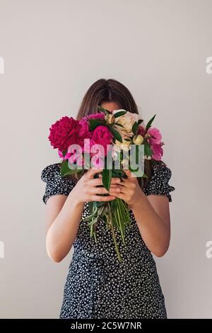 Unrecognizable girl in cute dress holding big bouquet of pink and red peonies Stock Photo