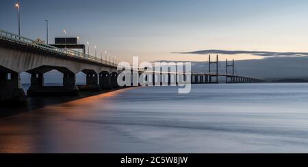 The Second Severn Crossing bridge carrying the M4 motorway between England and Wales is lit at dusk by streetlights and the trails of passing traffic. Stock Photo