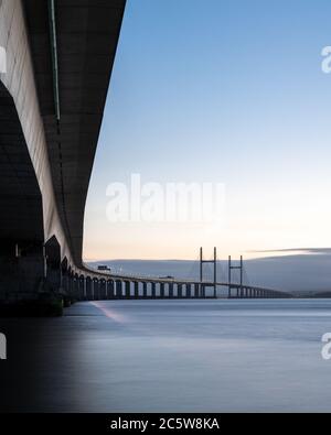 The Second Severn Crossing bridge carrying the M4 motorway between England and Wales is lit at dusk by streetlights and the trails of passing traffic. Stock Photo