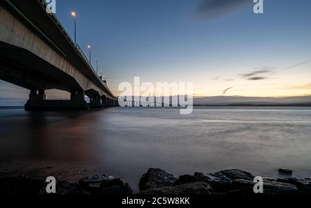 The Second Severn Crossing bridge carrying the M4 motorway between England and Wales is lit at dusk by streetlights and the trails of passing traffic.