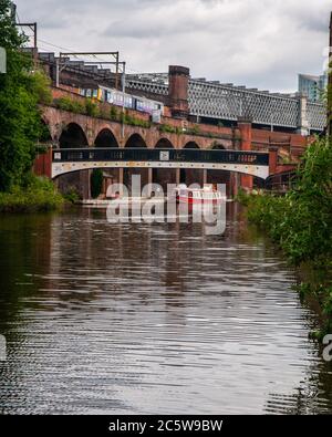 A Class 142 'Pacer' train travels along a Victorian brick viaduct above the Bridgewater Canal at Castlefield Basin in Manchester. Stock Photo