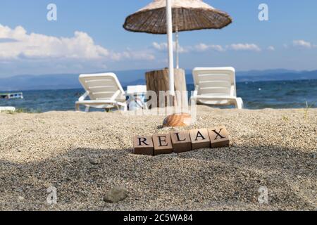 The word relax from wooden cubes. Close-up on the beach sand. Stock Photo