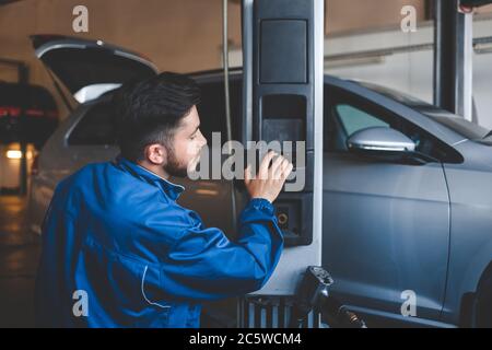 Auto mechanic lifts a car on a lift. Car repair Stock Photo