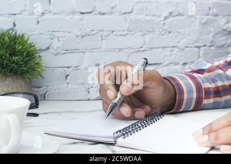 Close up of man hand writing with pen on notepad  Stock Photo