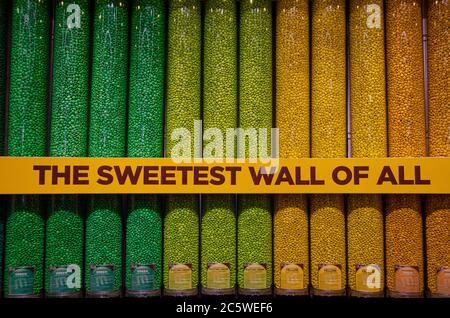 Various types of candies, jellies and sweets to buy, in pick and choose candyshop, with a 'The sweetest wall of all' sign Stock Photo