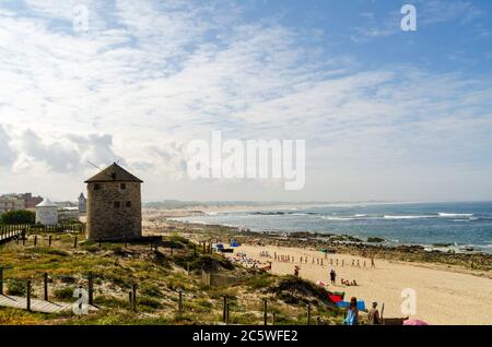 Portuguese Mill Houses in the dunes by a beach full of tourists by the ocean in Apulia during sunny summer weather Stock Photo