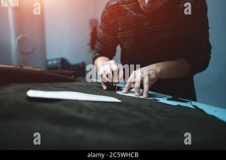 man shaping leather for shoe with knife on factory Stock Photo