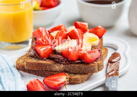 Toast with chocolate paste, banana and strawberries for breakfast. Stock Photo