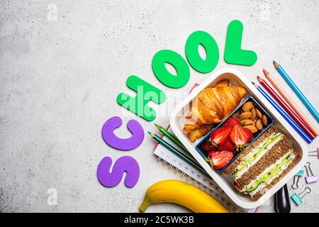 Back to school concept. Lunch box with a sandwich, croissants and snacks for school. School background with the inscription - school. Stock Photo