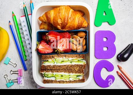 Back to school concept. Lunch box with a sandwich, croissants and snacks for school. School background with the inscription. Stock Photo