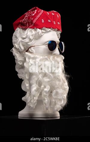 White plaster statue of a bust of Apollo Belvedere with a long white beard in sunglasses and a red bandana shawl on his head Stock Photo