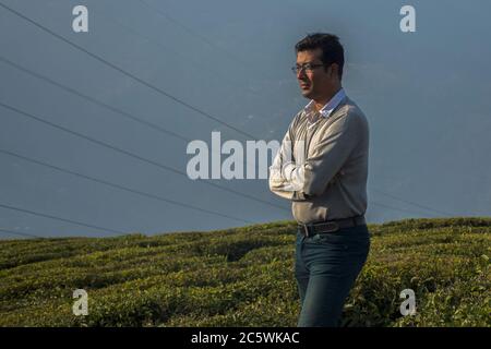 a young Indian male model standing in tea garden wearing t-shirt and jeans Stock Photo