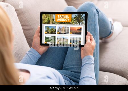 Woman Using Online Travel Agency Website Opened On Digitral Tablet At Home Stock Photo