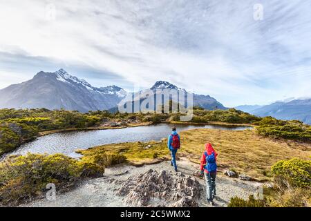 Hiking couple walking on adventure hike at Routeburn Track during sunny day. Hikers carrying backpacks tramping on Key Summit Track. People on Stock Photo