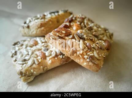 On the table on thick paper is a pastry covered with seeds and nuts. Stock Photo